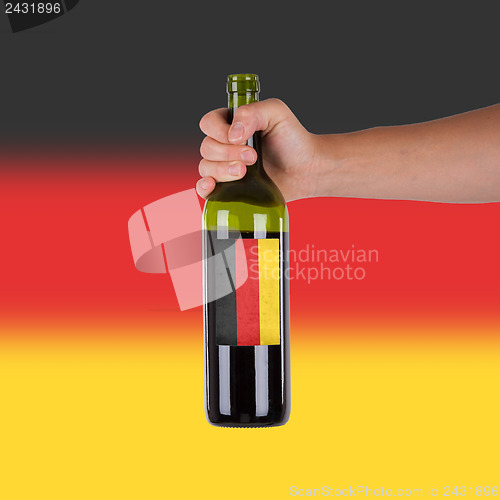 Image of Hand holding a bottle of red wine