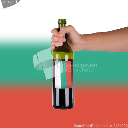 Image of Hand holding a bottle of red wine