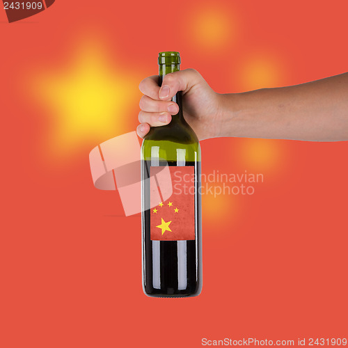 Image of Hand holding a bottle of red wine