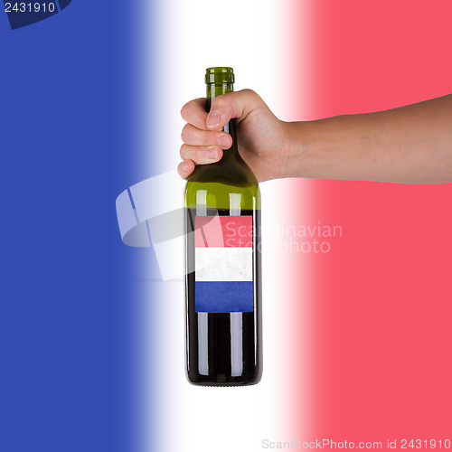 Image of Hand holding a bottle of red wine