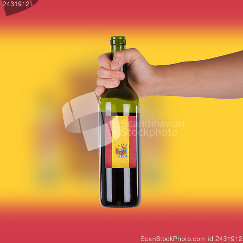 Image of Hand holding a bottle of red wine