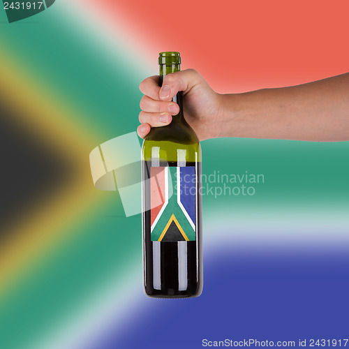 Image of Hand holding a bottle of red wine