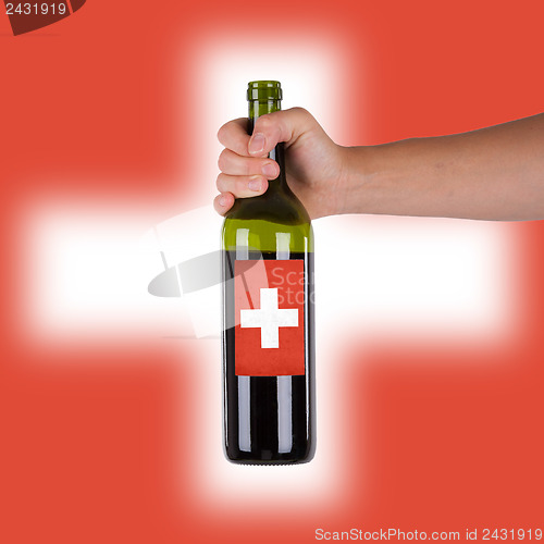 Image of Hand holding a bottle of red wine