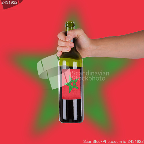 Image of Hand holding a bottle of red wine