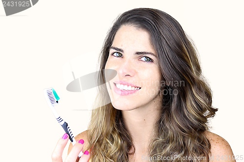 Image of Beautiful young lady holding toothbrush and smiling