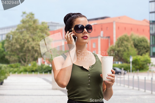 Image of attractive young woman with smartphone and sunglasses outdoor