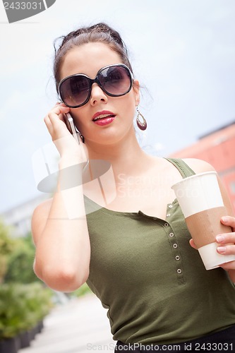 Image of attractive young woman with smartphone and sunglasses outdoor