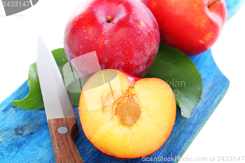 Image of Whole and half of plum on the blue board.