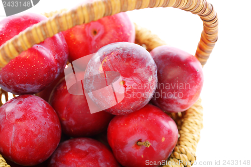 Image of Ripe red plums in a basket close up.