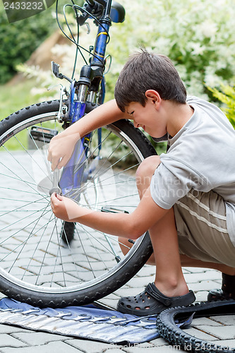 Image of Teenager repairing his bike, changing broken tyre