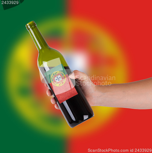 Image of Hand holding a bottle of red wine