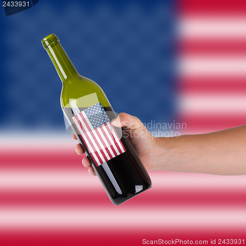 Image of Hand holding a bottle of red wine