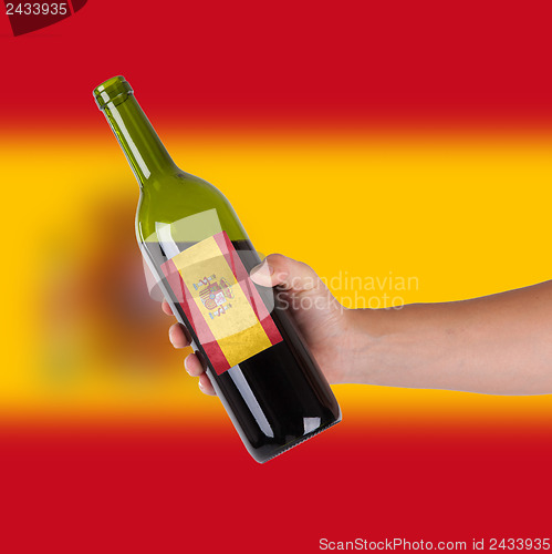 Image of Hand holding a bottle of red wine