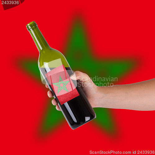 Image of Hand holding a bottle of red wine