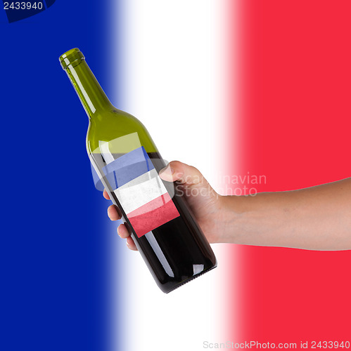 Image of Hand holding a bottle of red wine