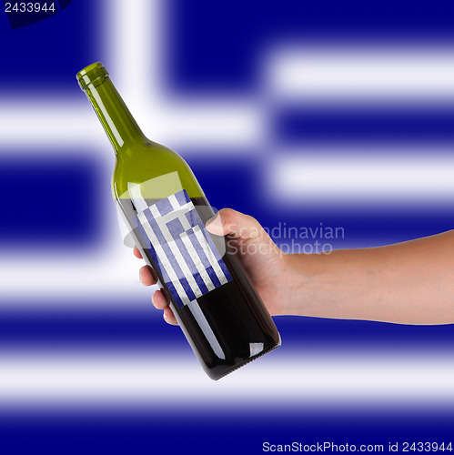 Image of Hand holding a bottle of red wine