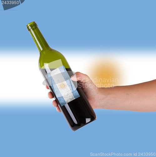 Image of Hand holding a bottle of red wine