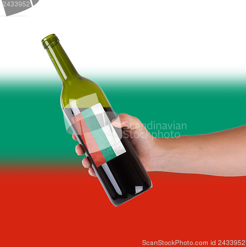 Image of Hand holding a bottle of red wine