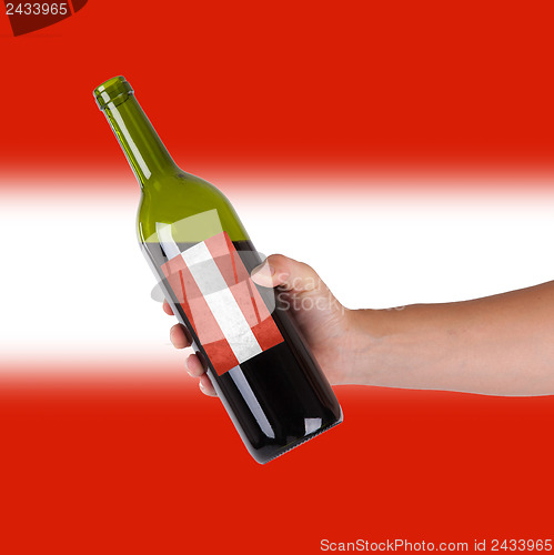 Image of Hand holding a bottle of red wine