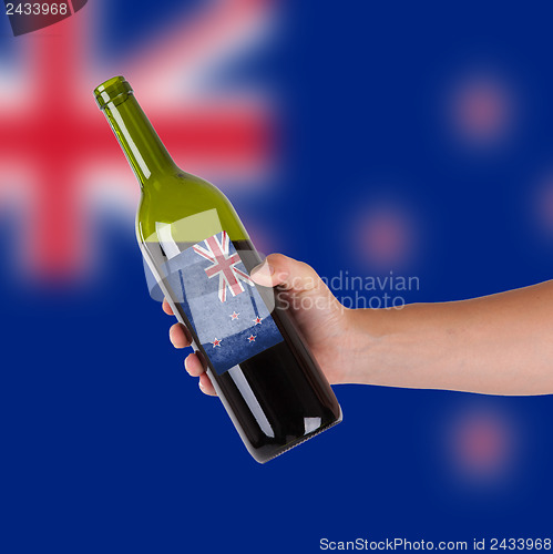 Image of Hand holding a bottle of red wine