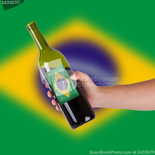 Image of Hand holding a bottle of red wine