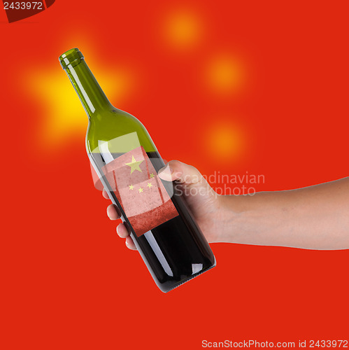 Image of Hand holding a bottle of red wine