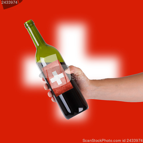 Image of Hand holding a bottle of red wine