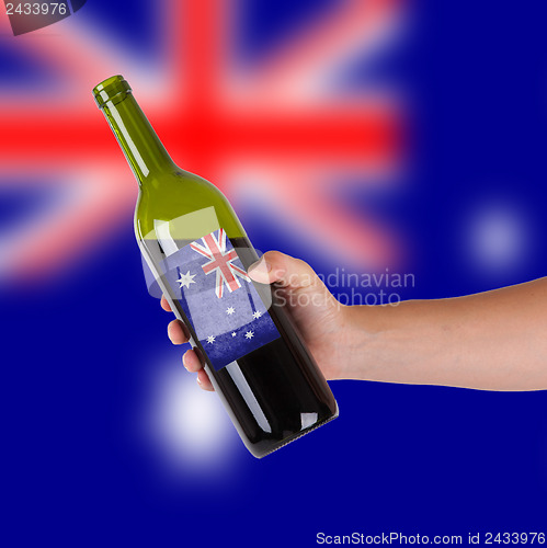 Image of Hand holding a bottle of red wine