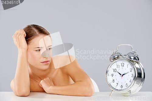 Image of Woman looking at an alarm clock in consternation