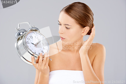 Image of Woman looking at an alarm clock in consternation