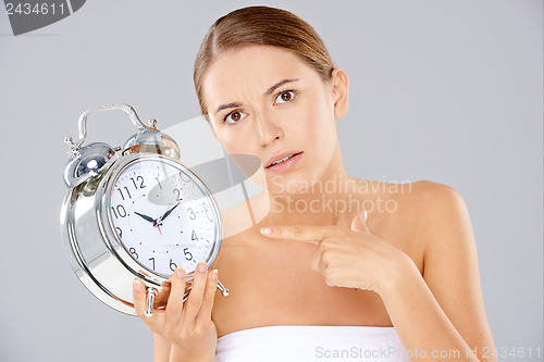 Image of Bored woman with an alarm clock in her hand