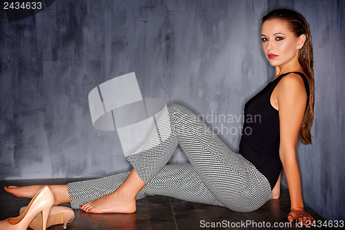 Image of Glamorous woman sitting barefoot on the floor