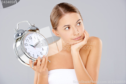 Image of Bored woman with an alarm clock in her hand
