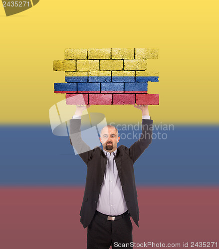 Image of Businessman holding a large piece of a brick wall