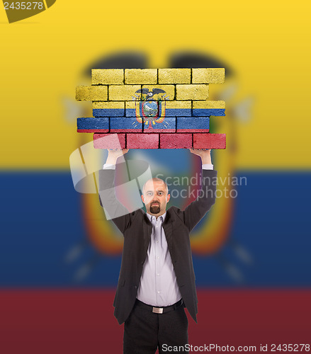 Image of Businessman holding a large piece of a brick wall