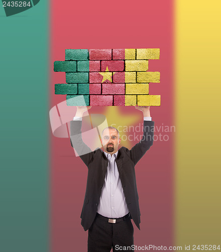 Image of Businessman holding a large piece of a brick wall