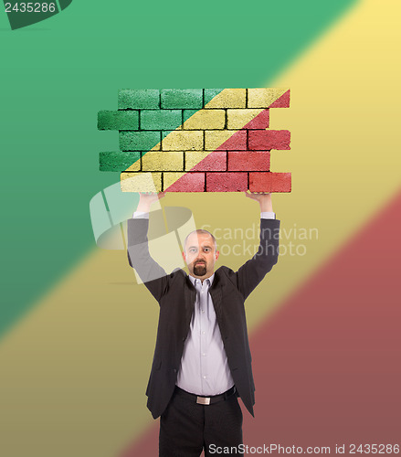 Image of Businessman holding a large piece of a brick wall