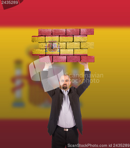 Image of Businessman holding a large piece of a brick wall