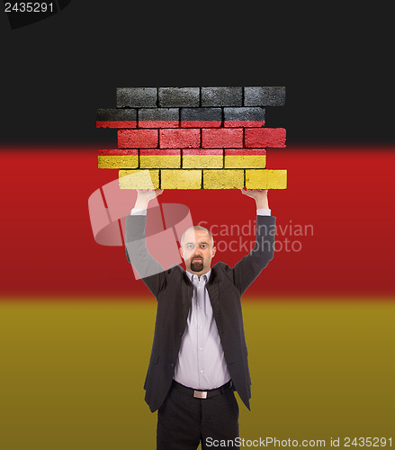 Image of Businessman holding a large piece of a brick wall