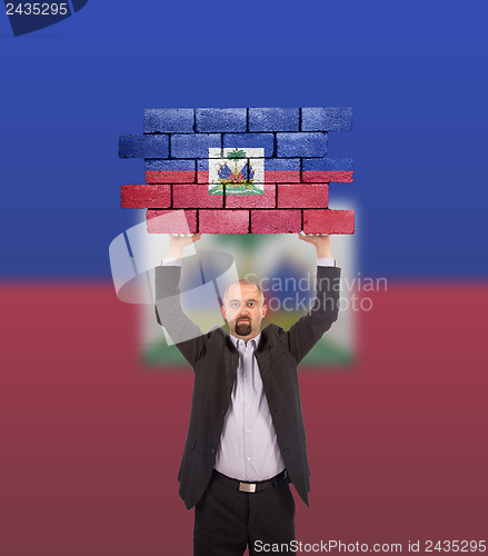 Image of Businessman holding a large piece of a brick wall