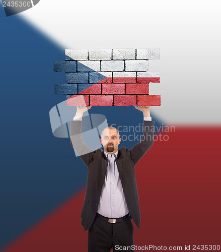 Image of Businessman holding a large piece of a brick wall