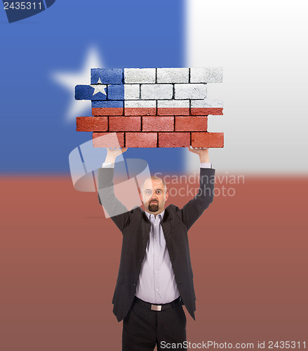 Image of Businessman holding a large piece of a brick wall