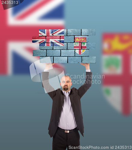 Image of Businessman holding a large piece of a brick wall