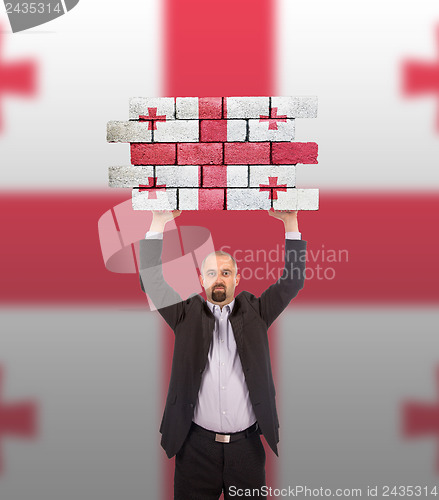 Image of Businessman holding a large piece of a brick wall