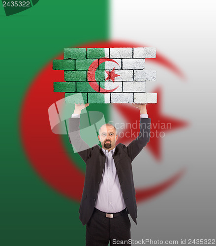 Image of Businessman holding a large piece of a brick wall