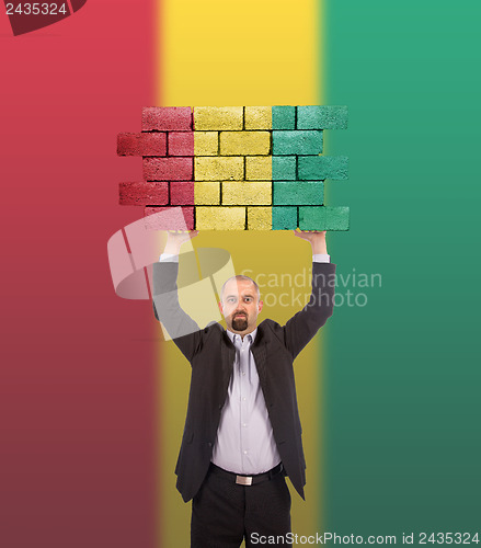 Image of Businessman holding a large piece of a brick wall