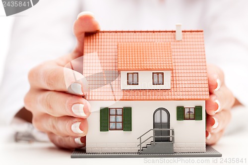 Image of pisture of man and woman hands holding paper house