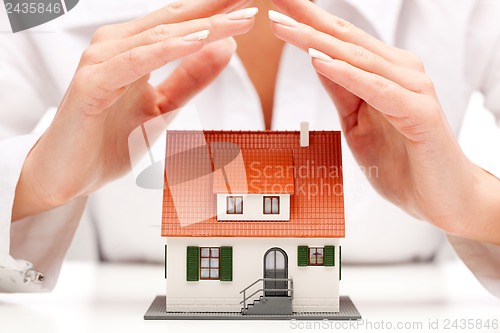 Image of Female hands saving small house with a roof