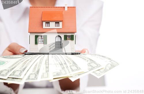 Image of Hands with money and miniature house on a white background