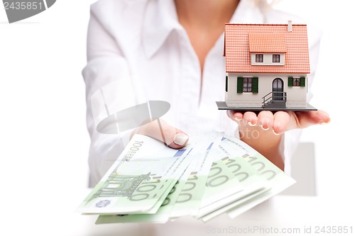 Image of Little house toy and money in woman's hands